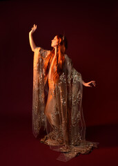 Full length fantasy portrait of beautiful woman model with red hair, goddess silk robes & gold...