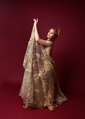Full length fantasy portrait of beautiful woman model with red hair, goddess silk robes & gold...