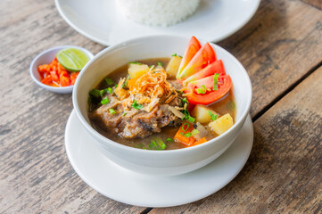 Delicious Oxtail Soup or Soup Buntut Served with Chili Sauce or Sambal and Steam Rice