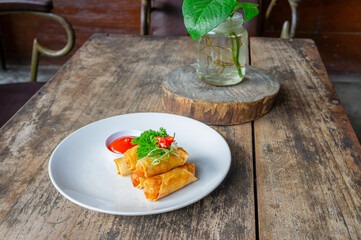Delicious Asian Snack Spring Rolls or Lumpia Served with Chili Sauce on White Plate