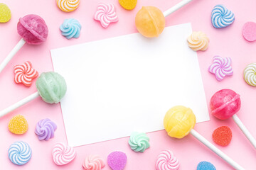 Sweet lollipops and candies and blank greeting card on pink background