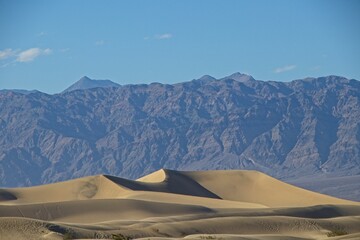 Fototapeta na wymiar The Mesquite Flat sand dunes rise above Stovepipe Wells in Death Valley, with the Panamint Range and Grapevine Mountains rising aove the valley on both sides.