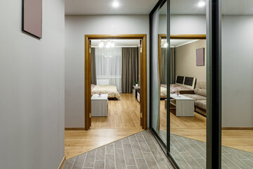 long corridor in interior of entrance hall of modern apartments with doors, cabinets, shelves and a mirror