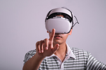 Surprised teen male student use vr glasses and looks at empty space with gray background. Virtual gadgets for entertainment, work, free time and study. Virtual reality metaverse technology concept.