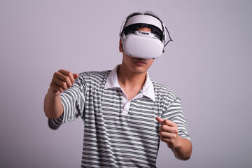 Surprised teen male student use vr glasses and looks at empty space with gray background. Virtual gadgets for entertainment, work, free time and study. Virtual reality metaverse technology concept.