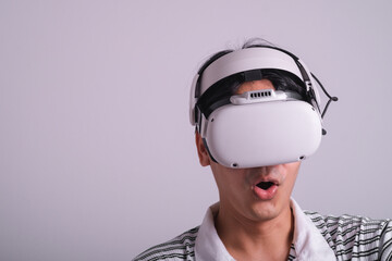 Surprised teen male student use vr glasses and looks at empty space with gray background. Virtual gadgets for entertainment, work, free time and study. Virtual reality metaverse technology concept.