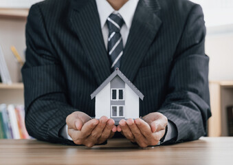 Concept of home and real estate Property insurance. Close up businessman of  hands sheltering modern house. .
