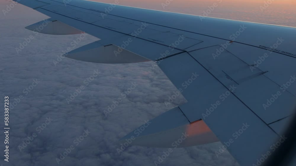 Poster view from the window of an airplane while flying above the clouds at dawn