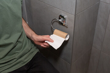 The man takes the last piece of toilet paper. Out of toilet paper. Awkward moment concept.