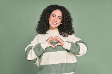 Young happy latin woman showing heart making shape with hands isolated on green background. Smiling female model expressing love and dating romance, warm affection, health care concept.