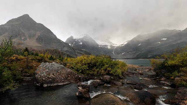 Scenery of Mount Assiniboine with stream flowing to Lake Magog in autumn forest on rainy day at Assiniboine provincial park