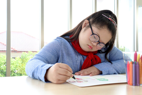 Happy children have fun study at home school, girl with down syndrome concentrate painting on paper in art classroom, education of kids with physical disability and intellectual concept