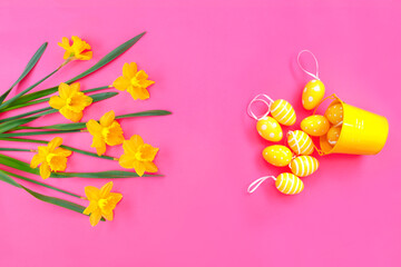Bouquet of beautiful yellow daffodils with Easter eggs on pink paper background. Creative greeting card.
