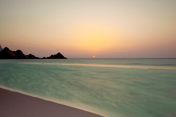 Sunset on the ocean coast. long exposure, calm ocean and rocks on the horizon.