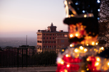 Christmas decoration shines in front of old Roman house and wide view of Rome