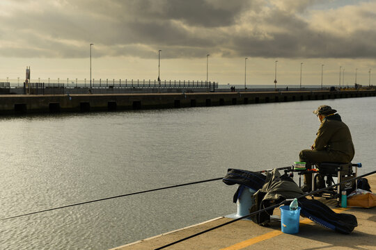 Italian fisherman sitting in front of the sea fishing with his fishing rod