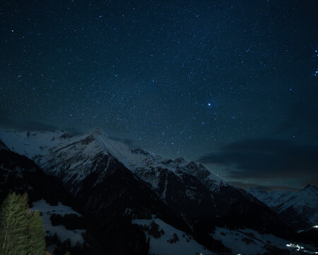 Snow covered mountain in Grisons, Swiss Alps, in long exposure is under starry sky.