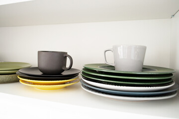 Dishes on a shelf in a white kitchen cabinet.