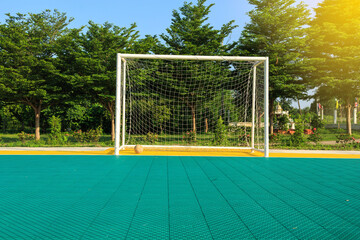 Soccer football on green rubber tree  field and goal post.