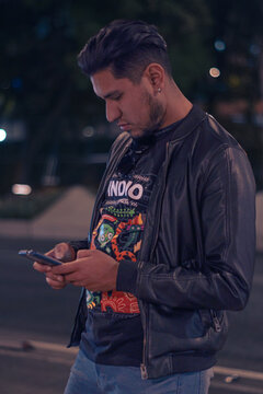 Hombre joven usando su celular en la mano escribiendo un texto