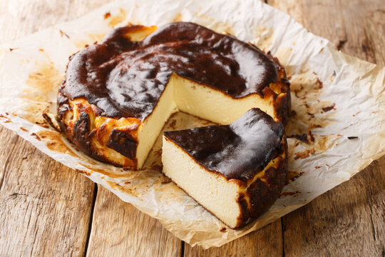 Traditional basque burnt cheesecake on a rustic wooden table closeup on the parchment paper. Horizontal