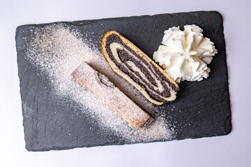 Poppy seed strudel with whipped cream sprinkled with sugar