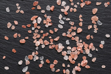 pink Himalayan salt used for spice and condiment in cooking on black slate background