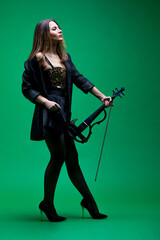 Violinist woman in the black blazer on the green background.