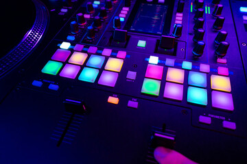 Close up of DJ mixing console in party light