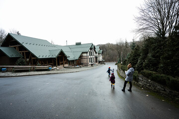 Obraz premium Family walking on path near wooden cottage in the forest. Country house.