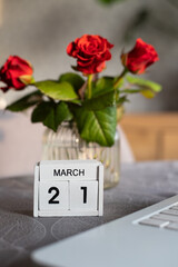 On a perpetual calendar, the date March 21 and red roses in a vase