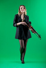 Violinist woman in the black blazer on the green background.