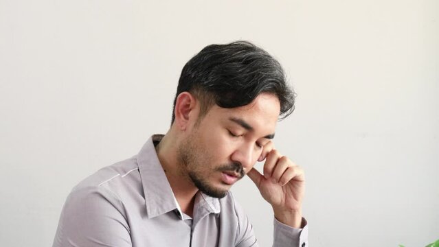 Handsome Asian male businessman in gray shirt sitting thinking and stressed.4k.
