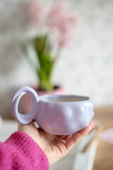 A beautiful cup filled with coffee in a woman's hand