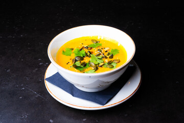 Pumpkin cream soup with parsley on gray stone and wooden background. Top view, copy space
