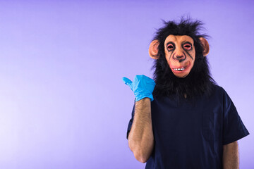 Disguised person in a monkey mask and doctor's outfit, pointing to the side with his finger, on...