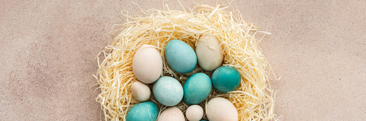 Naklejka na ściany i meble Colorful Easter eggs in a nest on a pastel pink background, top view, copy space, Easter banner