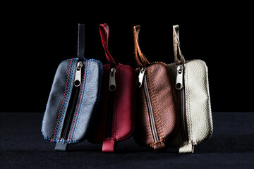 A group of different color leather keychain pouches, isolated on black background