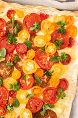 Puff pastry pie with colorful tomatoes and mozzarella, parsley and basil