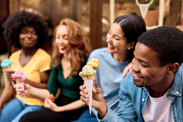 African man eating an ice cream with friends outdoors