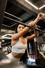 Fototapeta premium Young sporty girl in the gym resting after barbell exercises. Athletic body