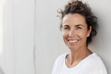 40 year old woman standing in front of a white wall. Generative AI.