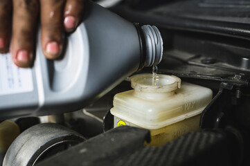 Auto mechanic adding brake fluid in brake fluid reservoir.