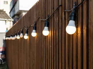 Warm lights garland bulbs hanging on brown wood pattern wall.