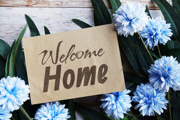 Welcome Home text message with flower decoration on wooden background