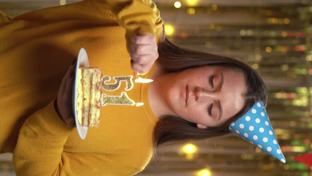 Beautiful happy young woman wearing sweater holding birthday cake number 51 golden candles burning by lighter. Concept of celebrating birthday and anniversary. POV.