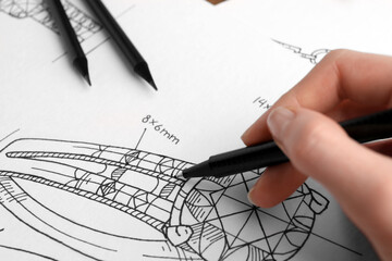 Jeweler drawing sketch of elegant ring on paper, closeup