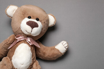 Cute teddy bear on gray background, top view. Space for text