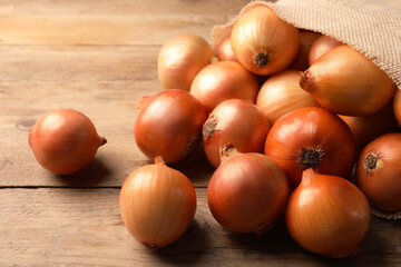 Many ripe onions on wooden table, closeup