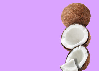 Stack of fresh coconuts on violet background. Space for text